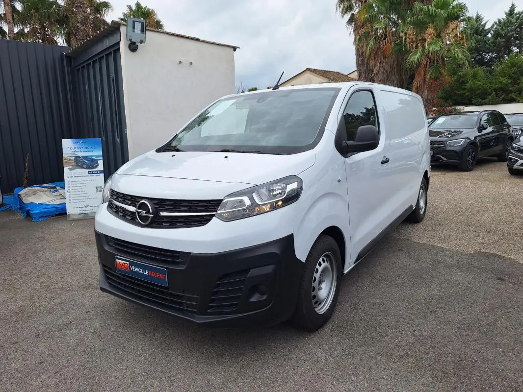 Opel Vivaro blanc en 3/4 avant droit, fourgon utilitaire avec porte latérale et pare-chocs noirs.