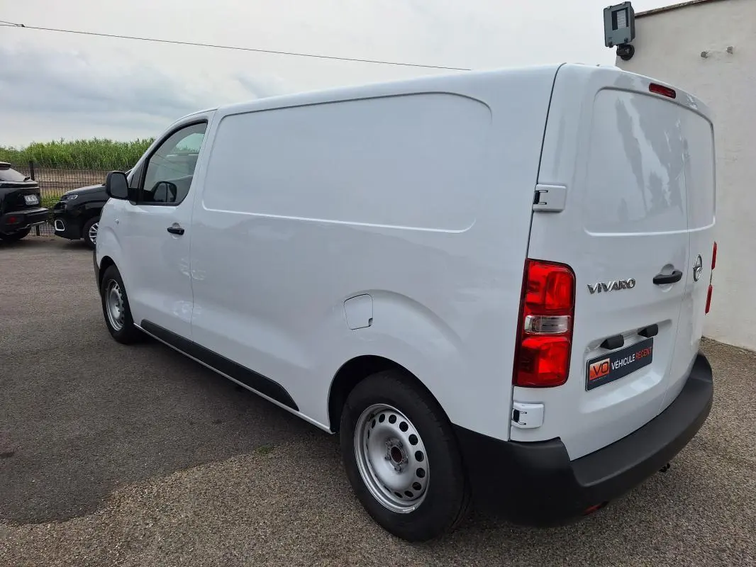 Vue 3/4 arrière droite d’un Opel Vivaro blanc utilitaire avec porte latérale et feux arrière rouges.