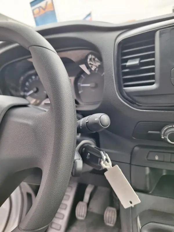 Vue rapprochée de l’intérieur noir du tableau de bord et du volant de l’Opel Vivaro blanc, avec clé insérée dans le contact.