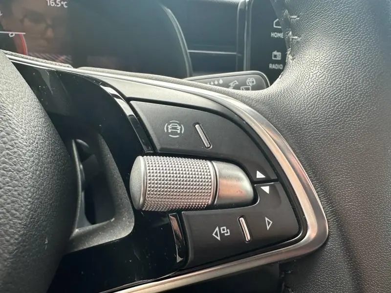 Gros plan sur les commandes multifonctions côté gauche du volant cuir d'une Skoda Scala blanc cristal.