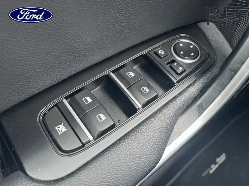 Gros plan sur les commandes de lève-vitres et rétroviseurs côté conducteur d'une KIA CEE'D SW noir Basalte métallisé.