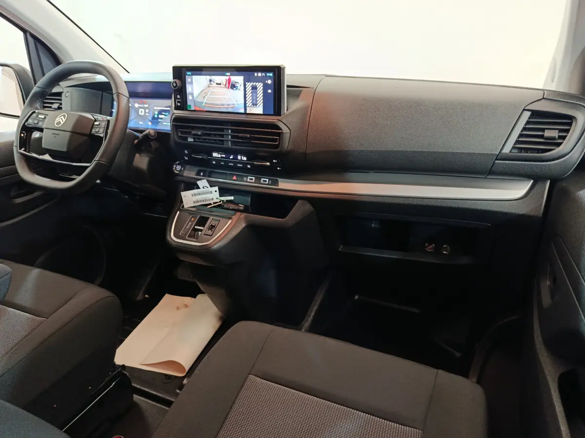 Vue intérieure avant du Citroën Jumpy XL 2025 noir, tableau de bord avec écran tactile et volant multifonctions.