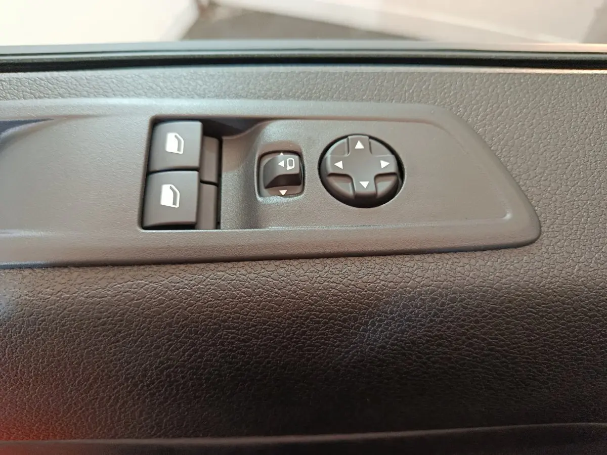 Gros plan sur les commandes de réglage des rétroviseurs et des vitres sur la porte intérieure d'un Citroën Jumpy XL noir.