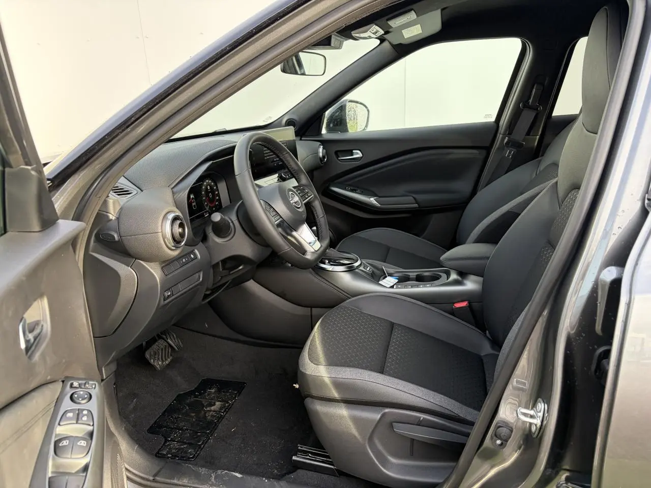 Intérieur noir du Nissan Juke 2 1.6 Hybrid 2025 vu côté conducteur, avec volant cuir et console centrale moderne.