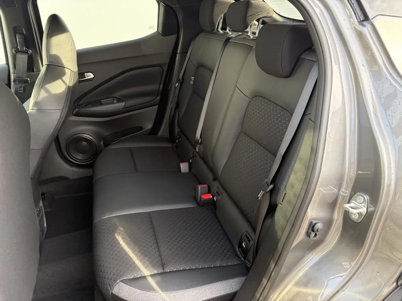 Vue intérieure côté droit de la banquette arrière noire avec ceintures grises du Nissan Juke II 1.6 Hybrid 2025.