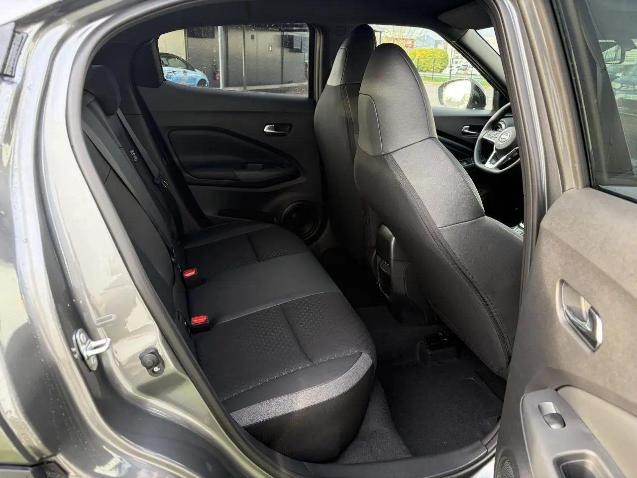 Vue intérieure côté gauche sur la banquette arrière noire et les sièges avant du Nissan Juke II 1.6 Hybrid N-Connecta.