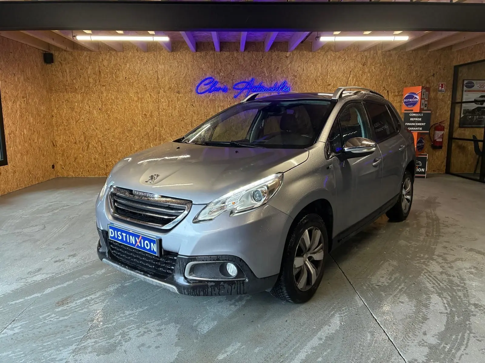 Peugeot 2008 gris vue 3/4 avant droit dans un garage avec toit ouvrant et jantes alliage.