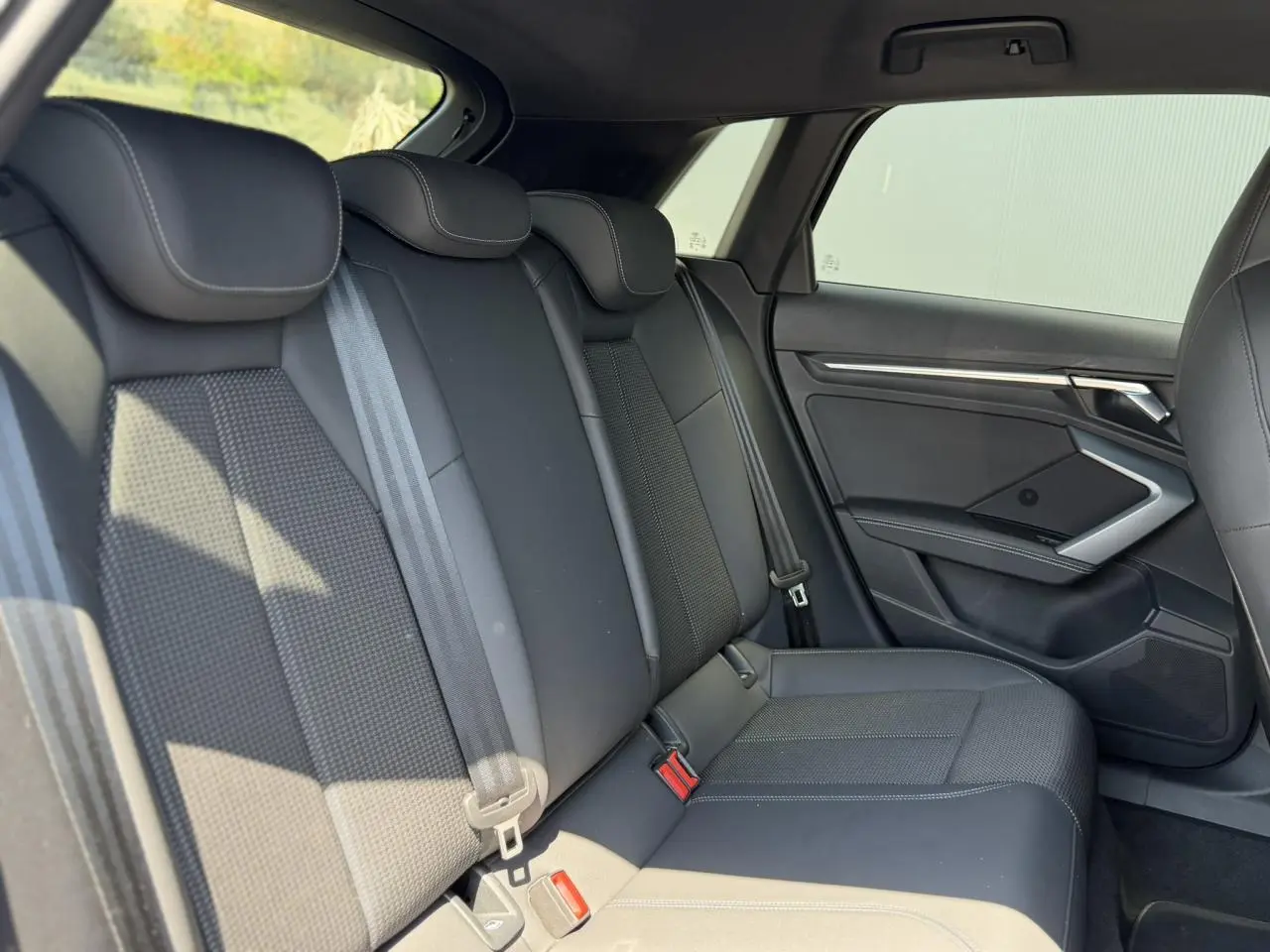 Vue latérale droite de la banquette arrière noire avec ceintures et garnitures tissu et cuir dans l'Audi A3 Sportback 2025.