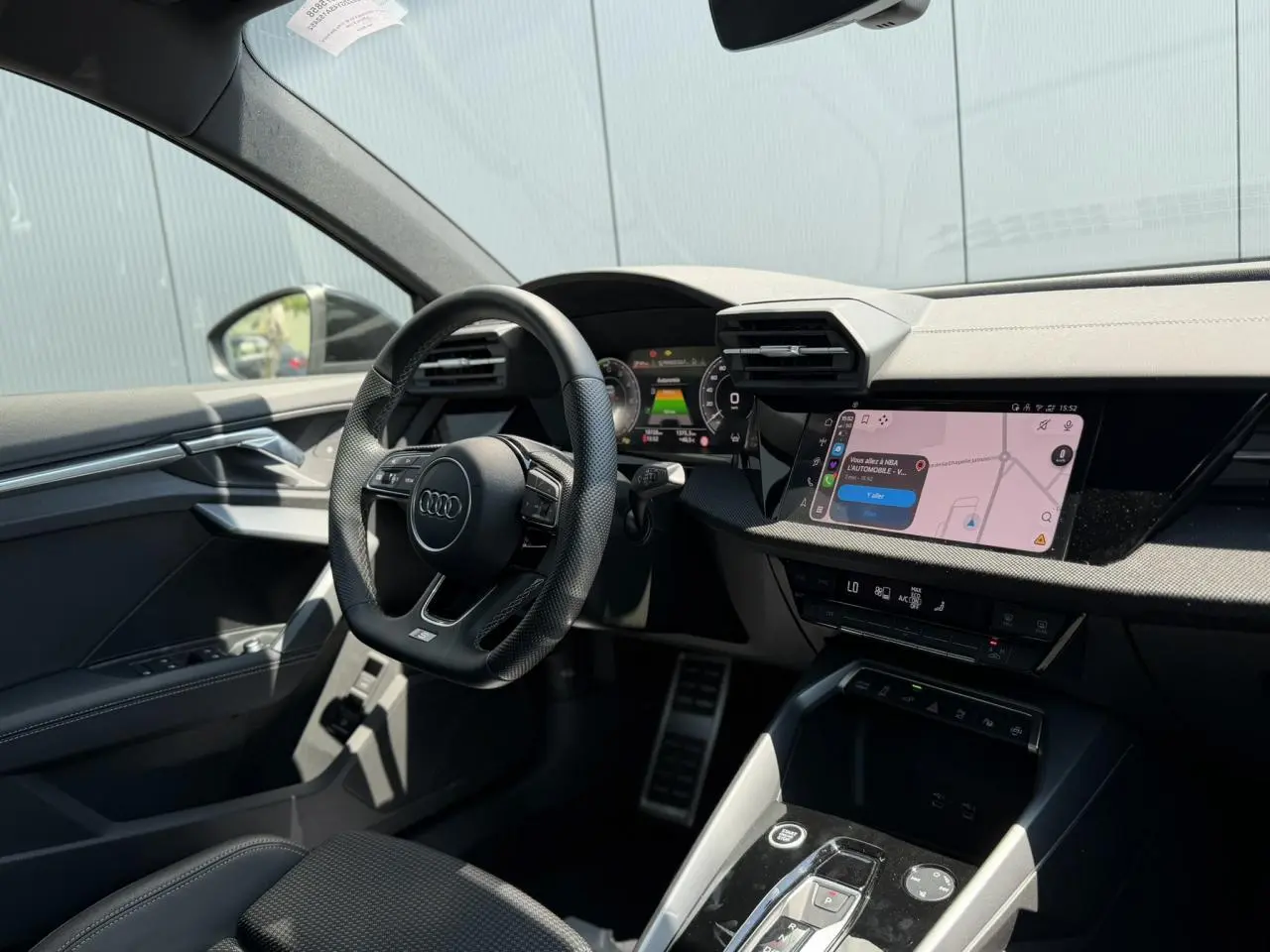 Vue intérieure côté conducteur de l'Audi A3 Sportback 2025, tableau de bord noir avec écran tactile de navigation.