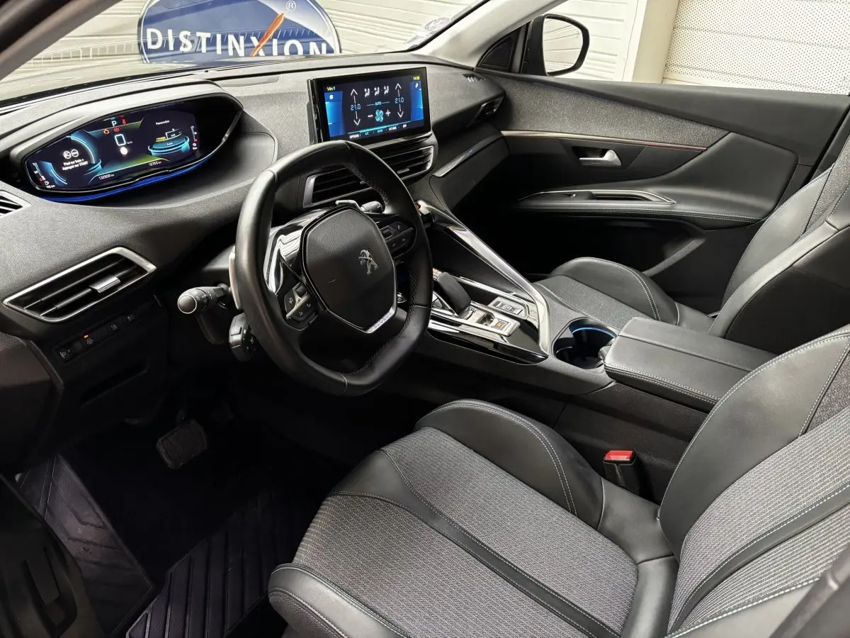 Intérieur avant droit du Peugeot 3008 hybride gris foncé, volant cuir, écran tactile et tableau de bord numérique.