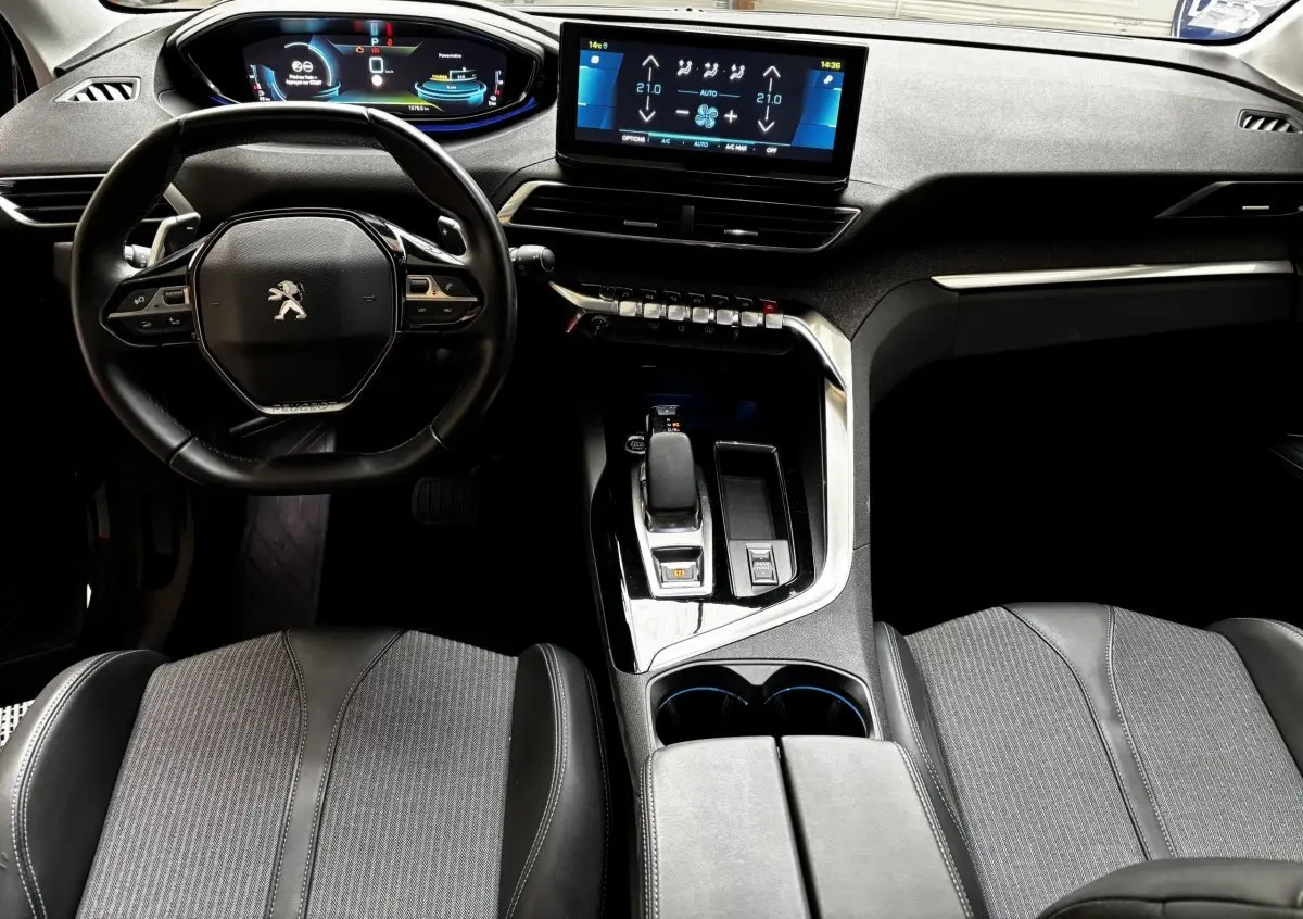 Vue intérieure avant du Peugeot 3008 gris foncé, volant cuir, écran tactile central et console moderne.