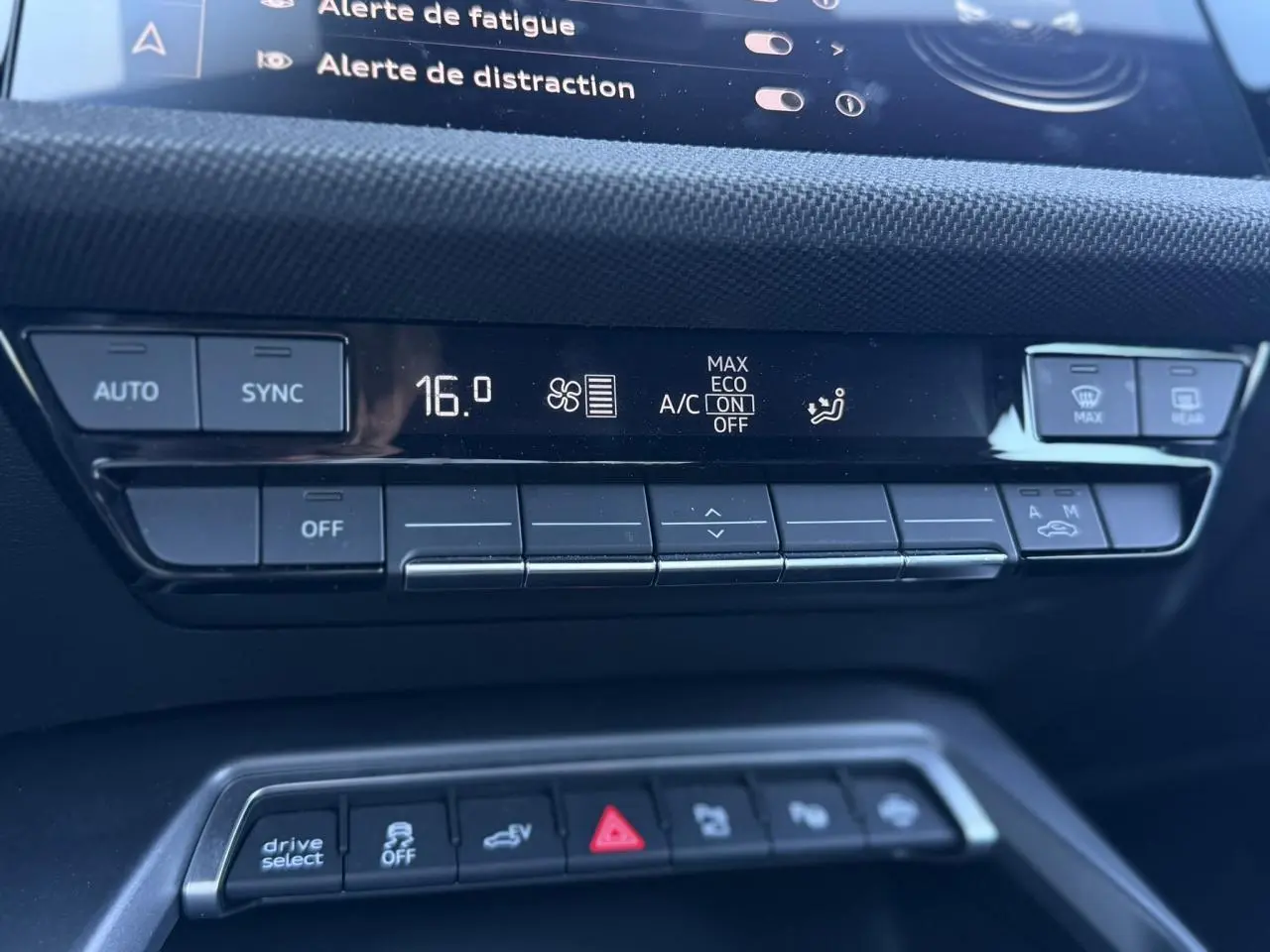 Gros plan sur la console centrale noire de l’Audi A3 Sportback blanche, affichant la climatisation digitale et les commandes.