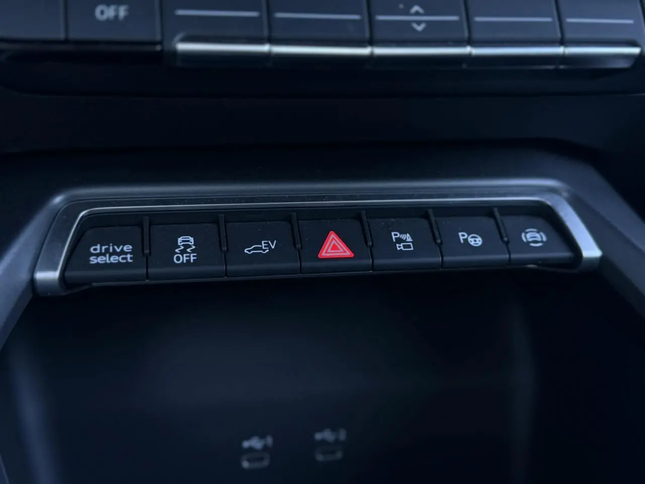 Gros plan sur la rangée de boutons de commande noire dans l'habitacle de l'Audi A3 Sportback blanc Glacier.