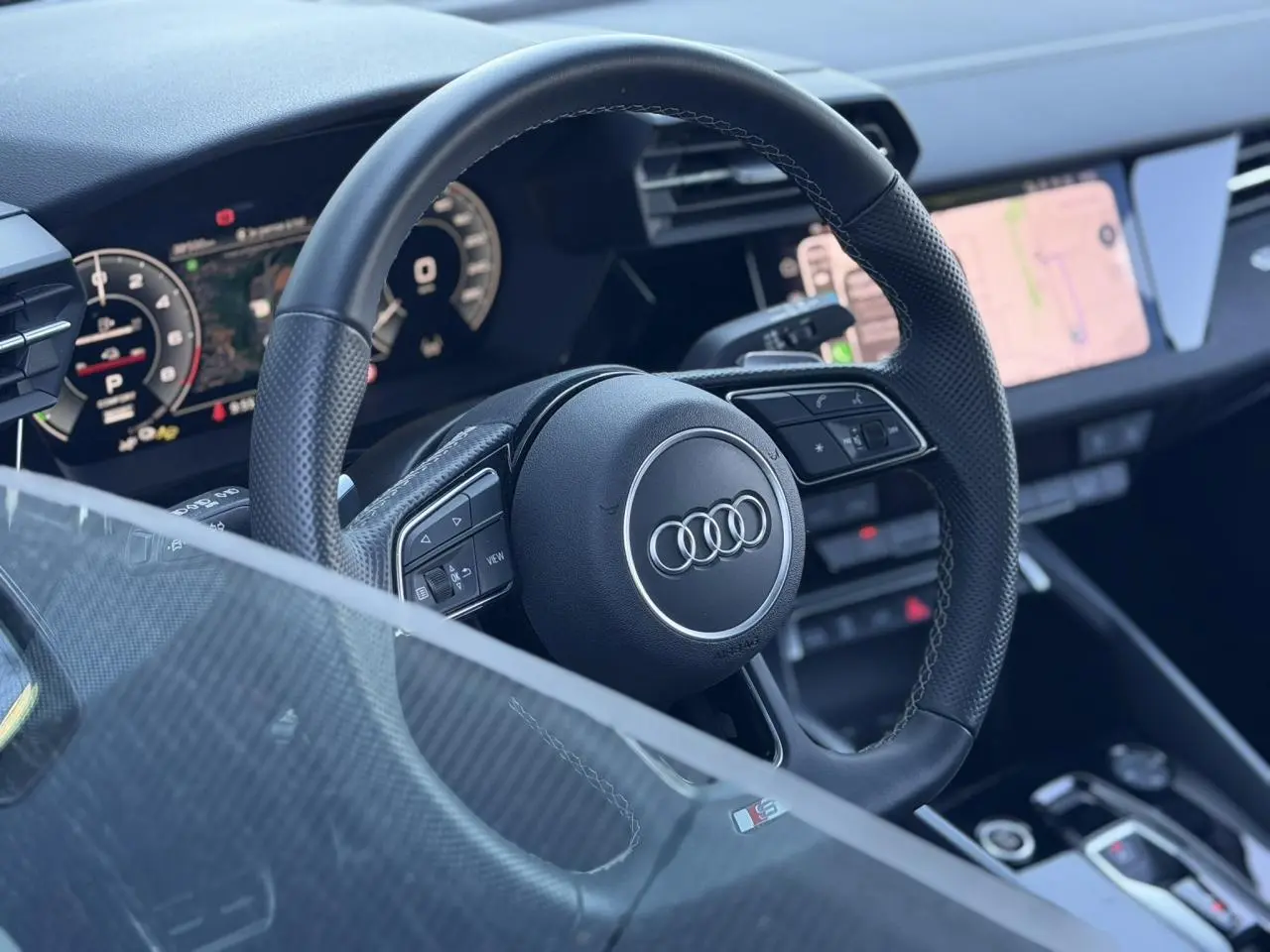 Vue rapprochée du volant cuir perforé noir avec logo Audi et tableau de bord numérique de l’Audi A3 Sportback 2025.