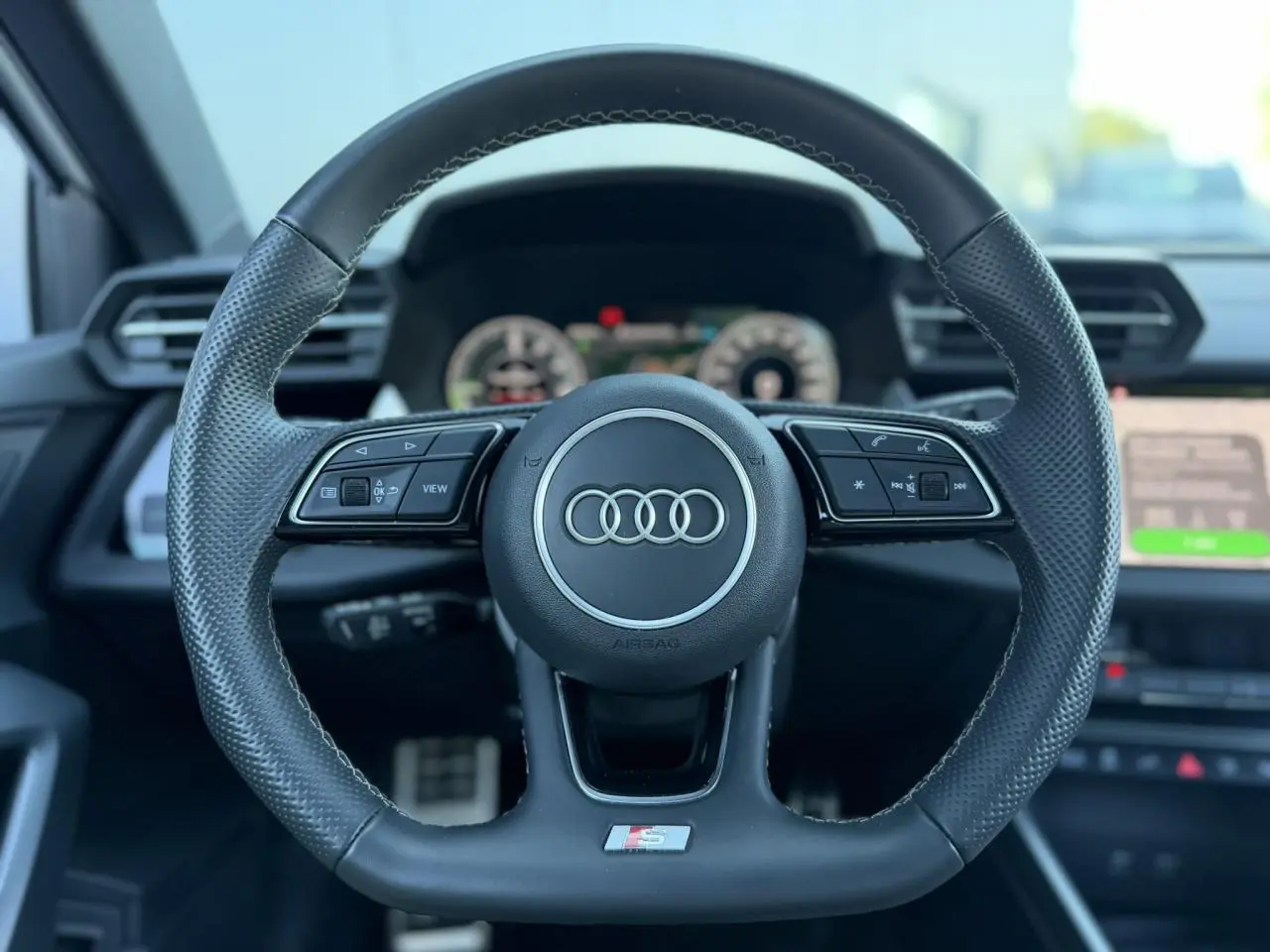 Volant sport en cuir perforé avec logo S Audi, vue frontale du poste de conduite intérieur noir.
