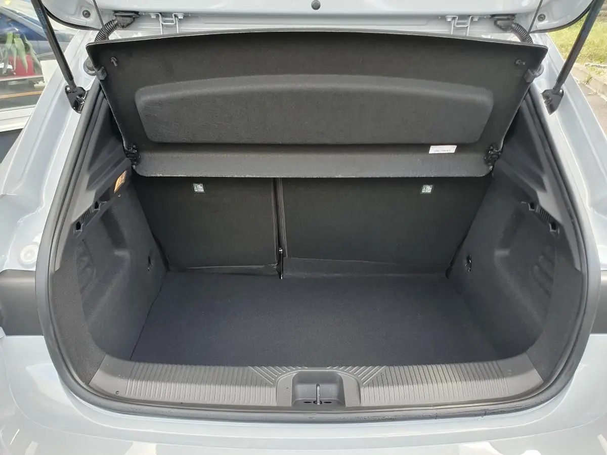 Coffre ouvert vu de l'arrière d'une Renault Clio VI gris Rafale, montrant l'espace de chargement vide et la tablette arrière relevée.
