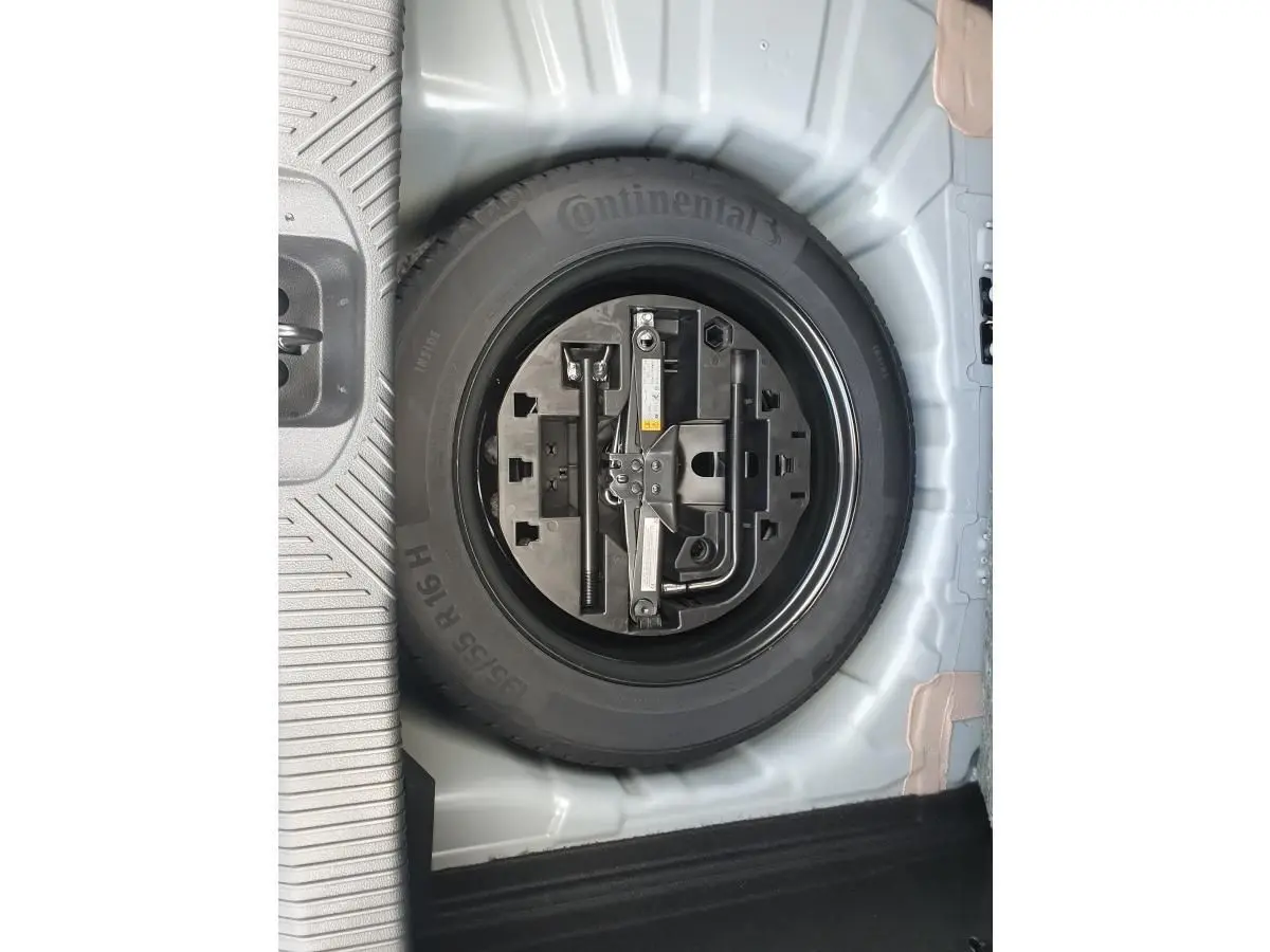 Gros plan sur la roue de secours noire avec outils intégrés dans le coffre d’une Renault Clio VI gris Rafale.