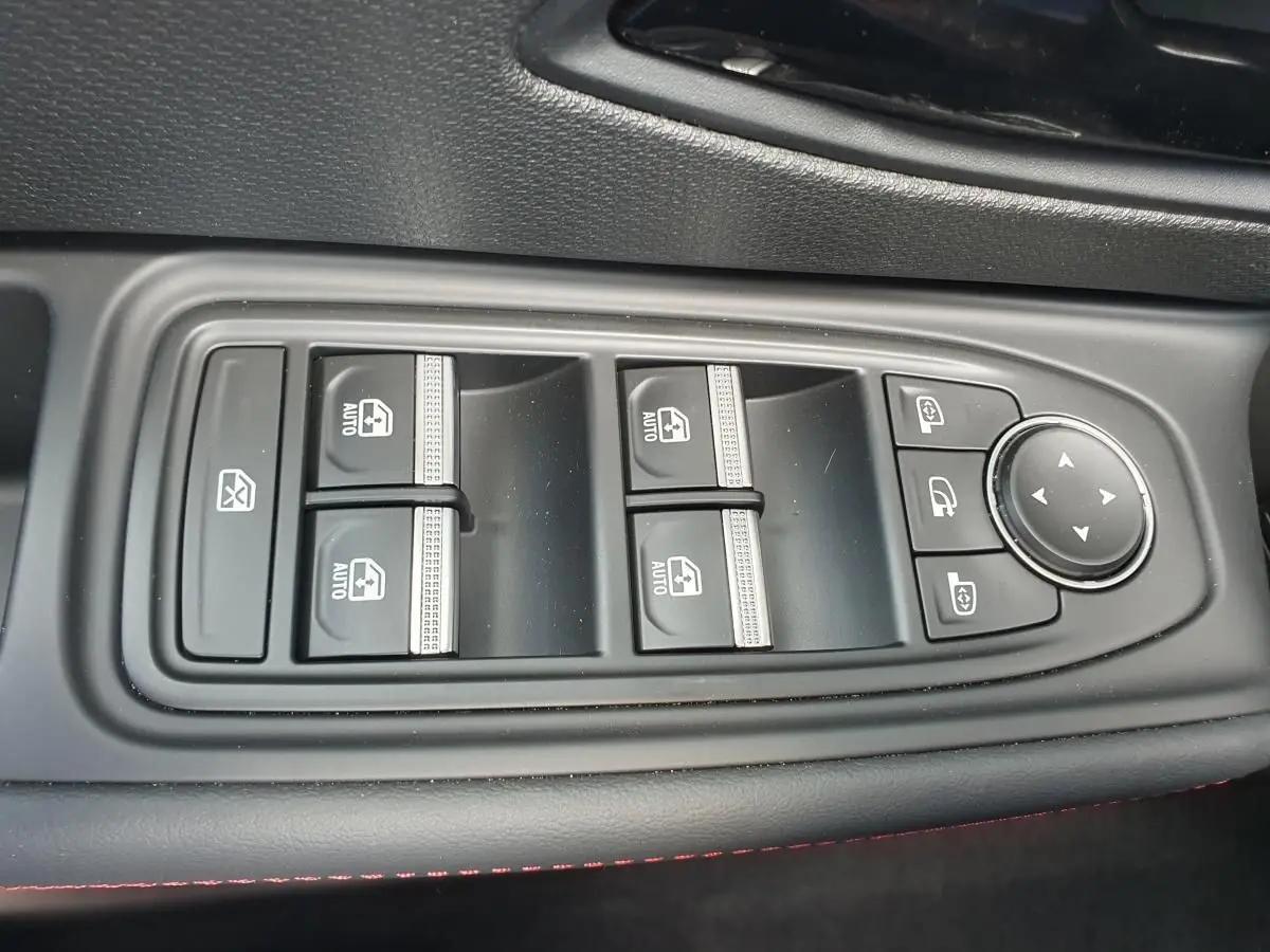 Gros plan sur les commandes de lève-vitres et rétroviseurs côté conducteur de la Renault Clio VI gris Rafale.