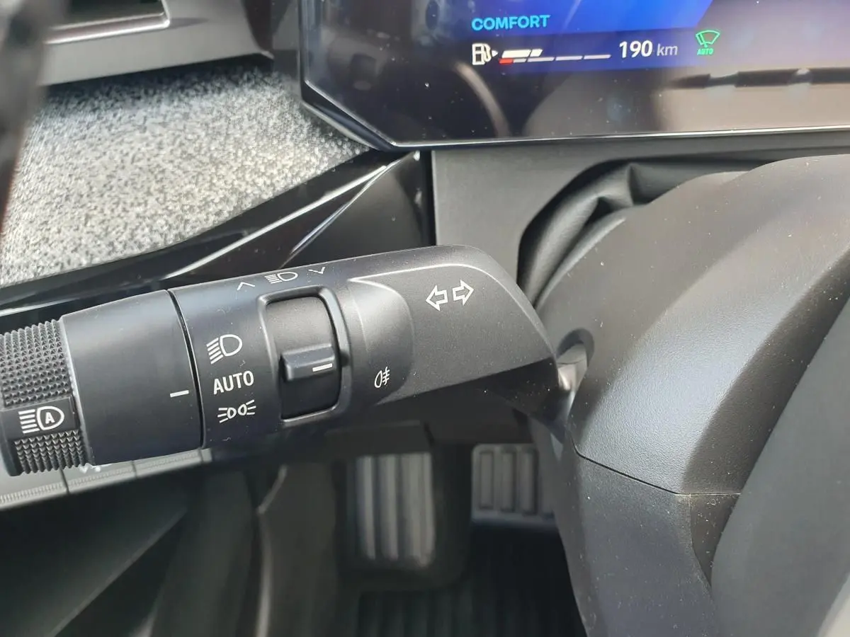 Gros plan sur la commande des feux et clignotants à gauche du volant dans l’habitacle de la Renault Clio VI gris Rafale.