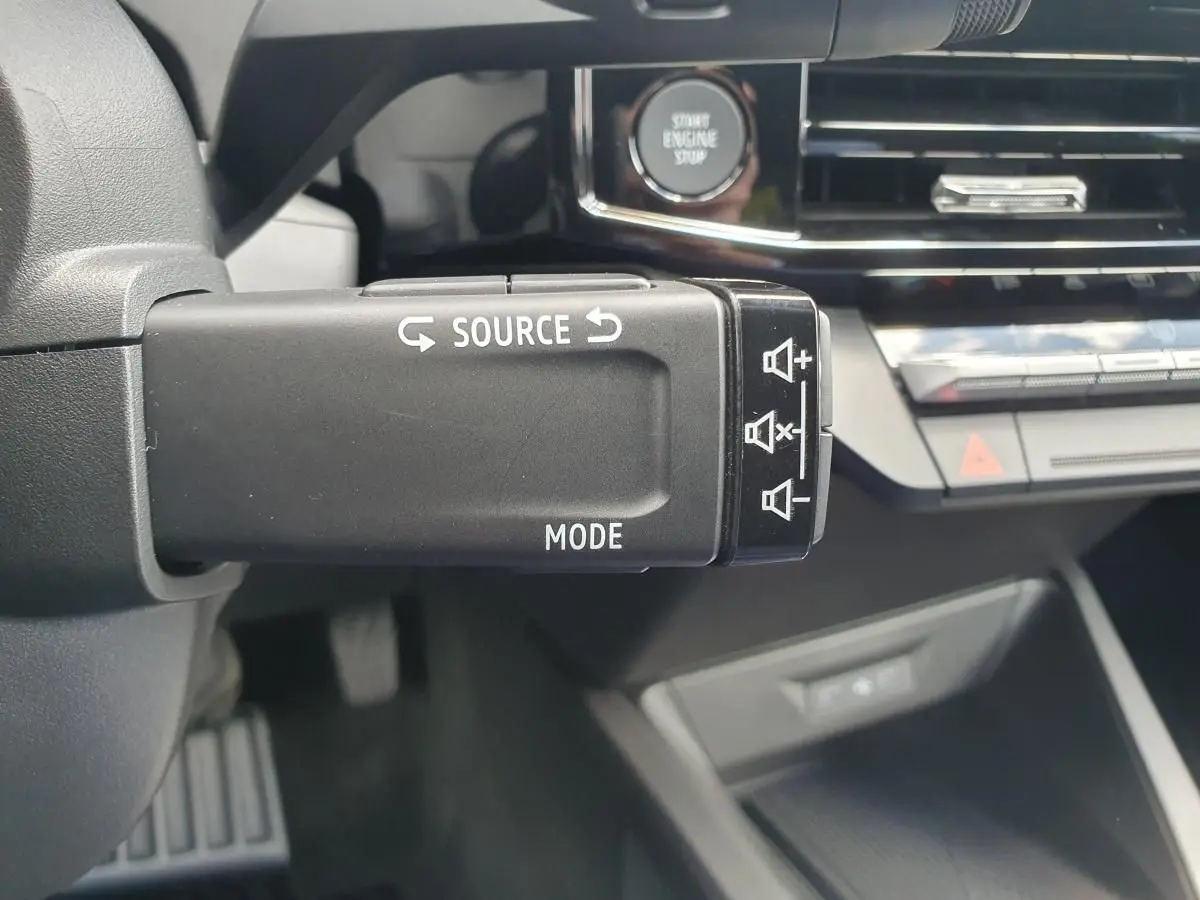 Gros plan sur la commande multimédia au volant de la Renault Clio VI, avec bouton start engine stop en arrière-plan.