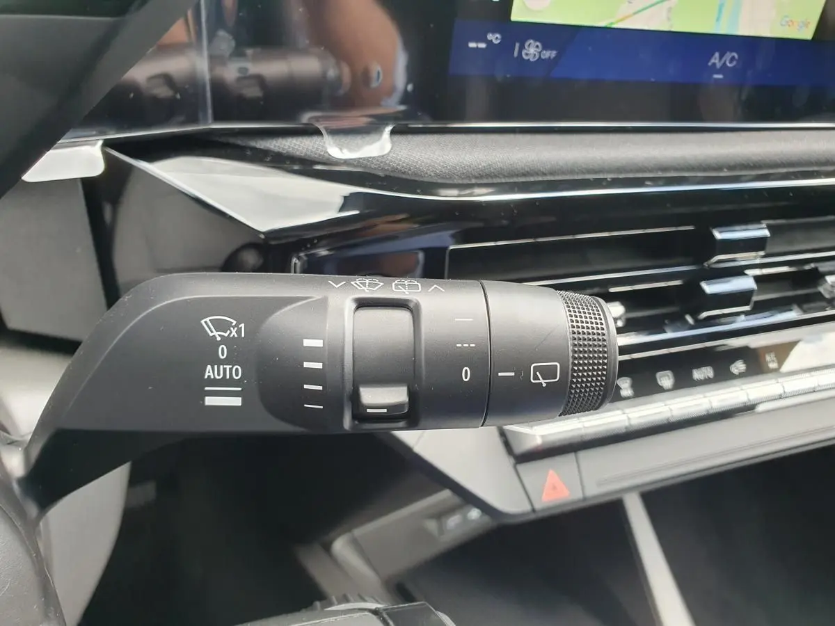 Gros plan sur la commande d’essuie-glace noire à gauche du volant dans l’habitacle gris et noir de la Renault Clio VI.