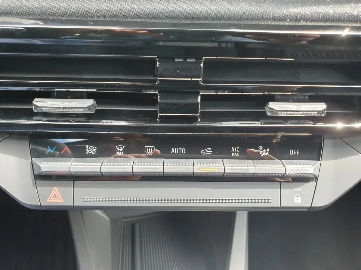 Gros plan sur la console centrale de la Renault Clio VI, montrant les commandes de climatisation et les aérateurs noirs.