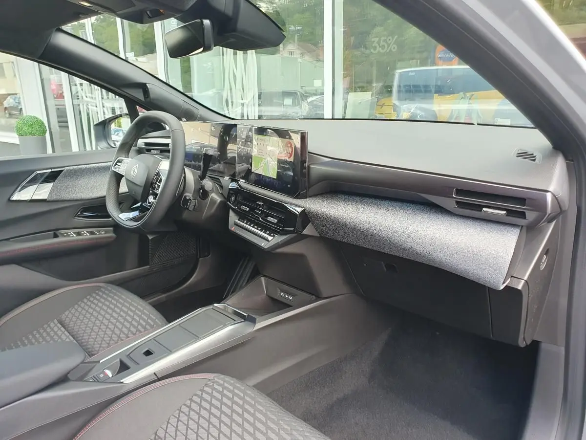 Vue intérieure côté passager de la Renault Clio VI avec tableau de bord moderne et écran tactile central.