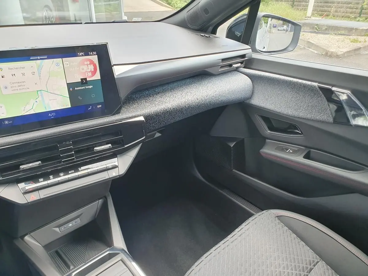 Vue intérieure côté passager de la Renault Clio VI 2026, tableau de bord moderne avec écran tactile et garniture grise texturée.