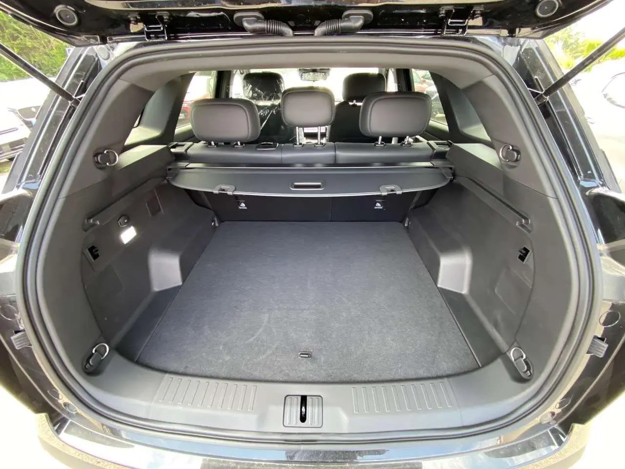 Coffre ouvert du JAECOO J7 1.5 PHEV Selective 2026 en carbone cristal noir, montrant un espace de chargement spacieux et propre.