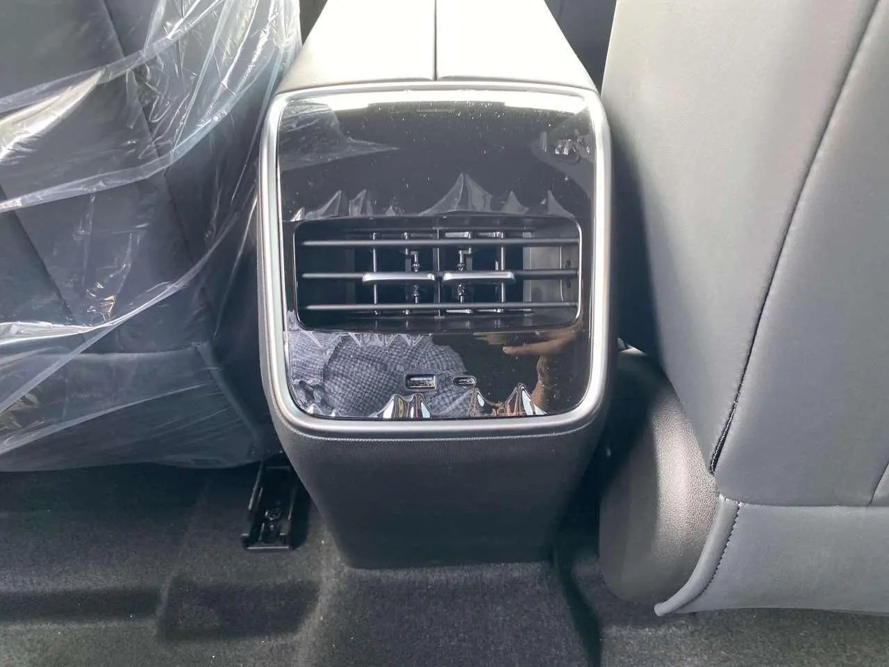 Vue rapprochée de la console arrière du JAECOO J7 1.5 PHEV en noir brillant avec prises USB visibles.