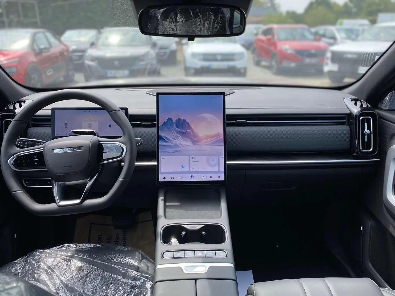Vue intérieure avant du JAECOO J7 1.5 PHEV en noir, avec grand écran tactile vertical et volant multifonction.