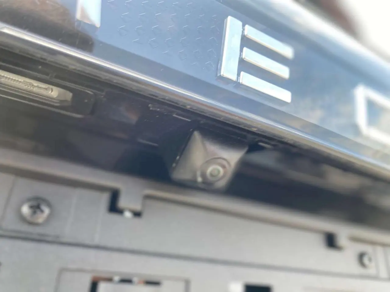 Gros plan sur la caméra de recul intégrée sous le logo arrière du JAECOO J7 2026 en noir Carbon Cristal.