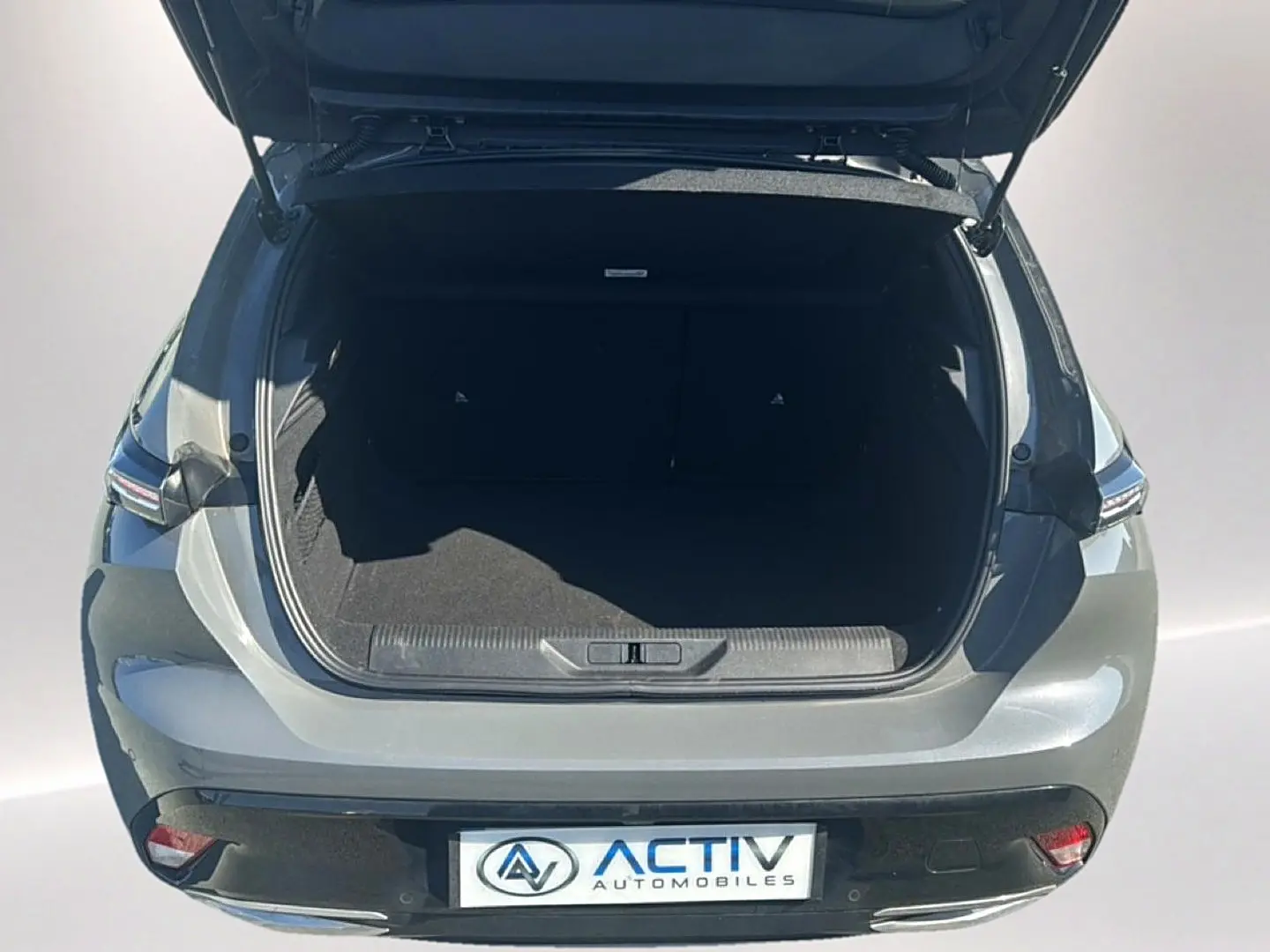 Vue arrière ouverte du coffre d'une Peugeot 308 gris selenium, mettant en valeur l'espace de chargement et les feux arrière LED.
