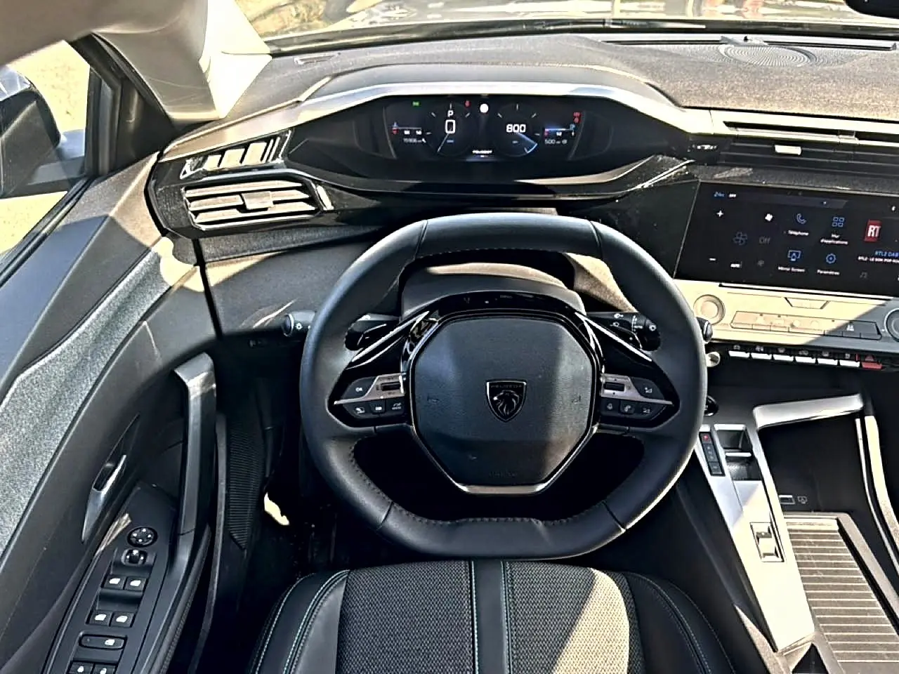 Vue intérieure centrée sur le volant multifonction noir et le tableau de bord digital du Peugeot 308 2025.
