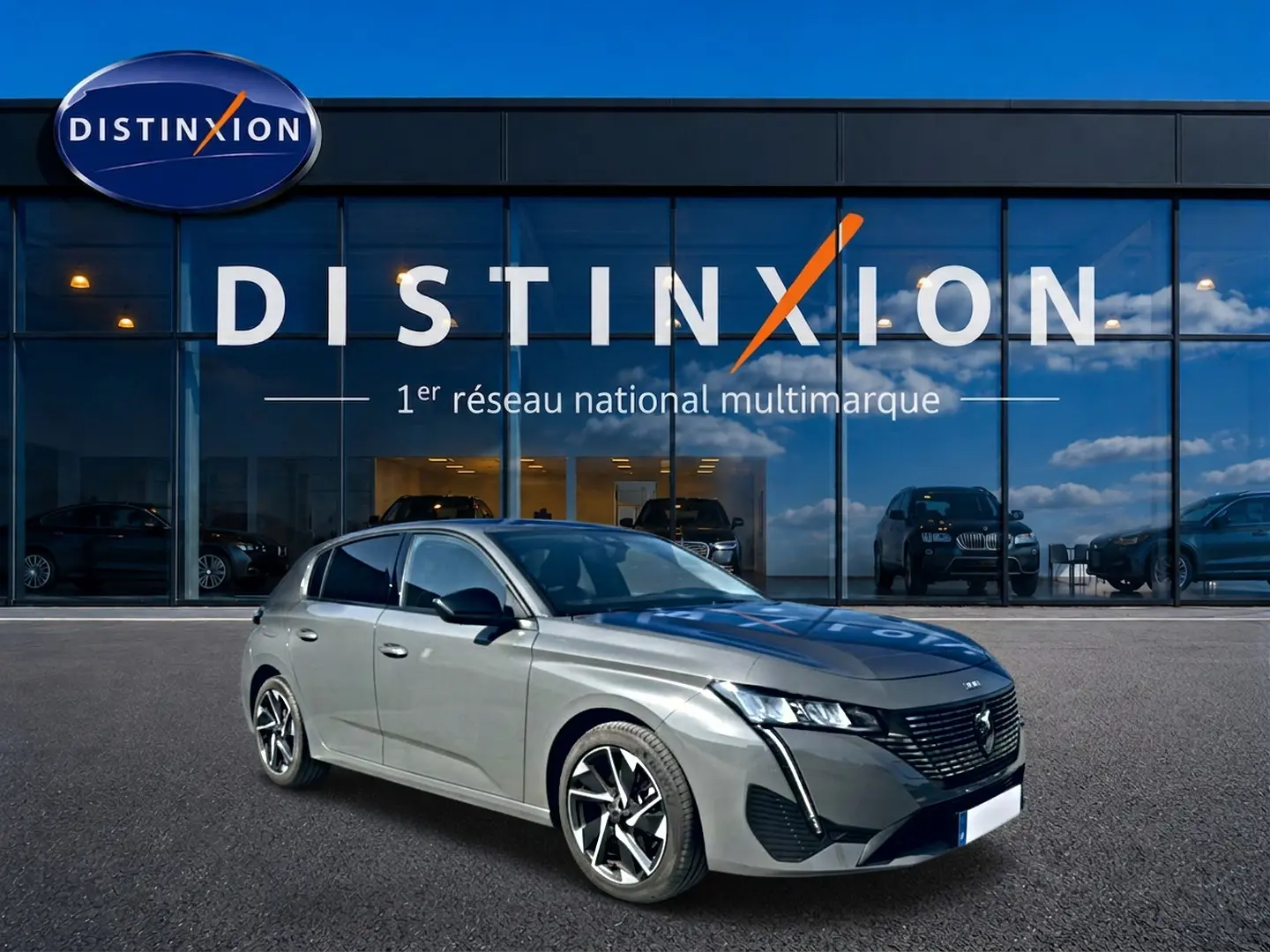 Peugeot 308 gris selenium vue 3/4 avant droit, avec jantes alliage et calandre noire distinctive, devant showroom Distinxion.