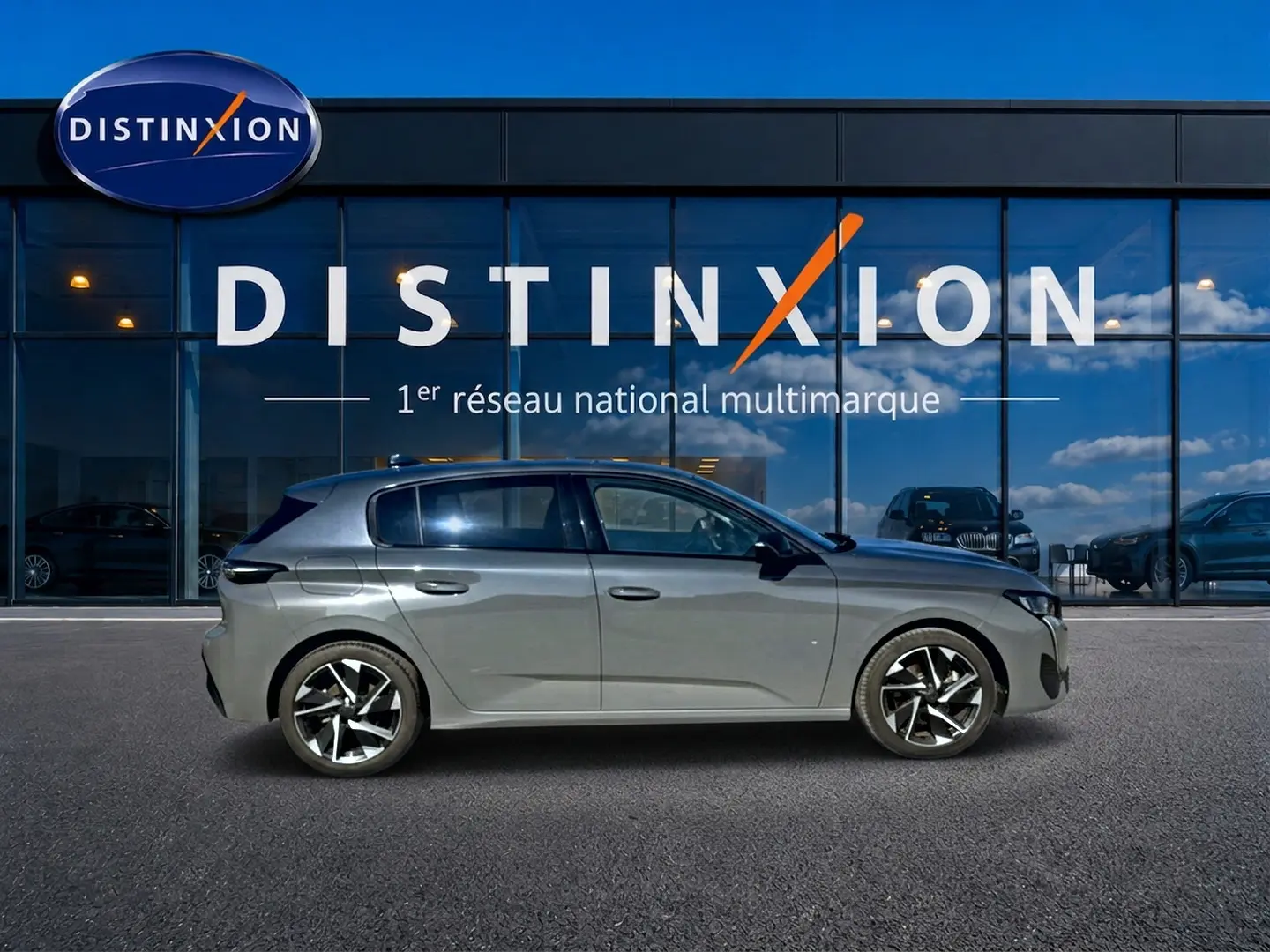 Peugeot 308 gris selenium vue de profil côté gauche devant une vitrine avec logo Distinxion.