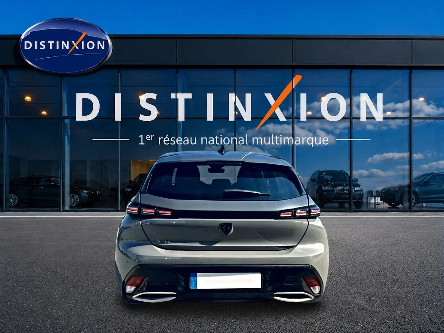 Vue arrière d'une Peugeot 308 gris selenium 2025 garée devant une vitrine avec logo Distinxion.