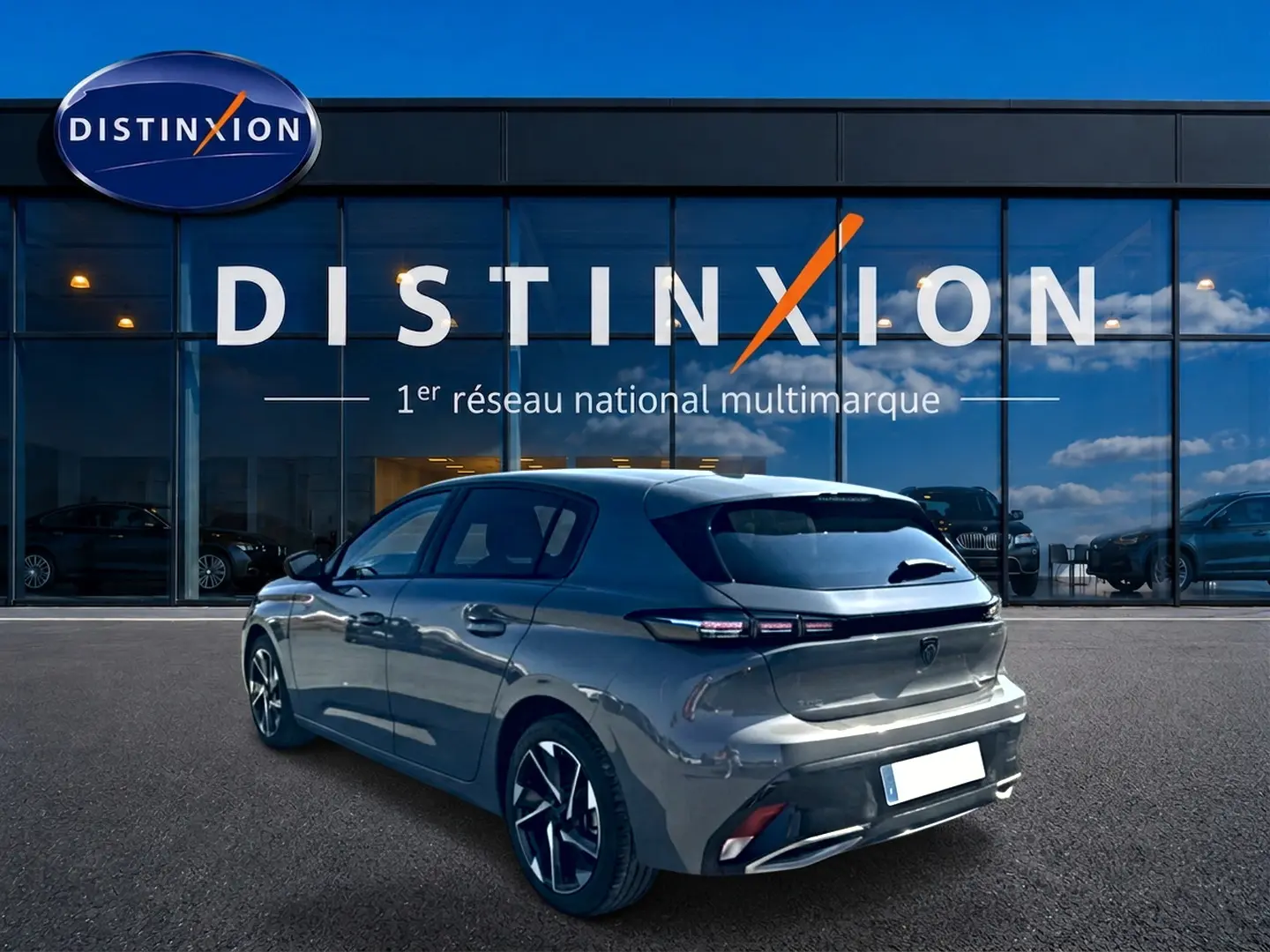 Peugeot 308 gris selenium vue 3/4 arrière droit, jantes alu et feux arrière LED distinctifs, devant concession Distinxion.