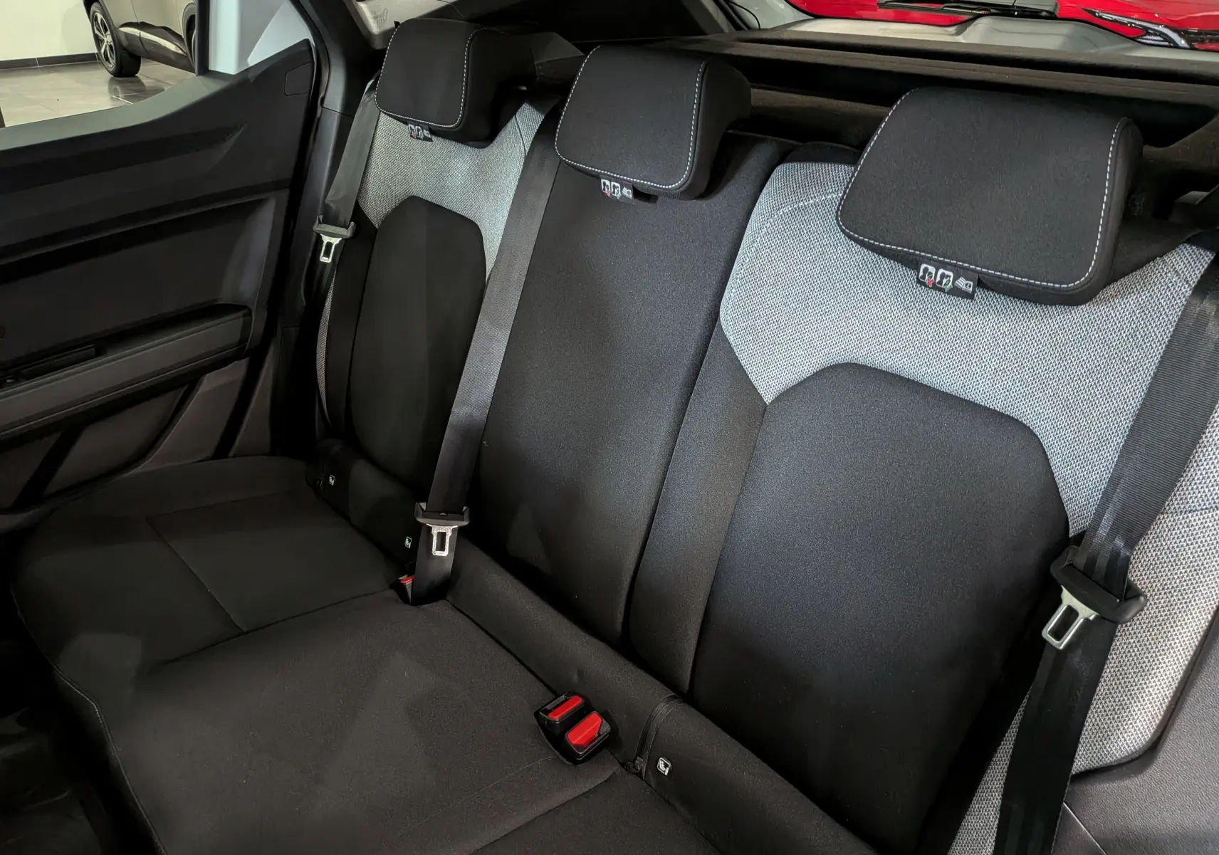 Vue intérieure des sièges arrière noirs et gris du Dacia Duster Hybrid-G 150 CH 4x4, avec ceintures de sécurité visibles.