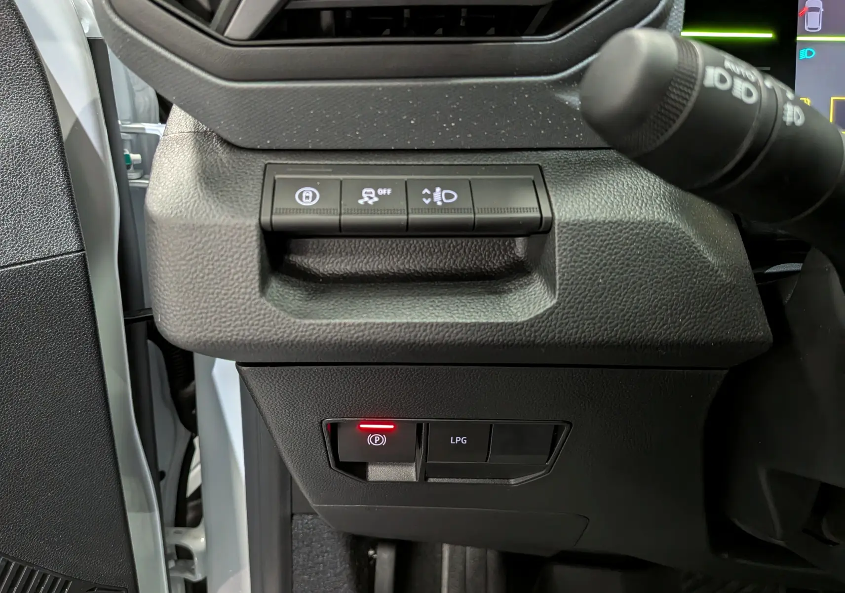 Vue rapprochée des commandes côté gauche du tableau de bord du Dacia Duster blanc Glacier, avec bouton frein à main électronique allumé.