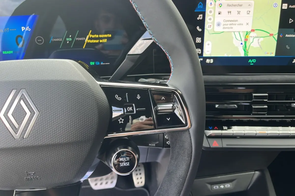 Gros plan sur le volant cuir multifonctions de la Renault Clio 6 E-Tech 160 Esprit Alpine avec tableau de bord numérique et écran tactile.