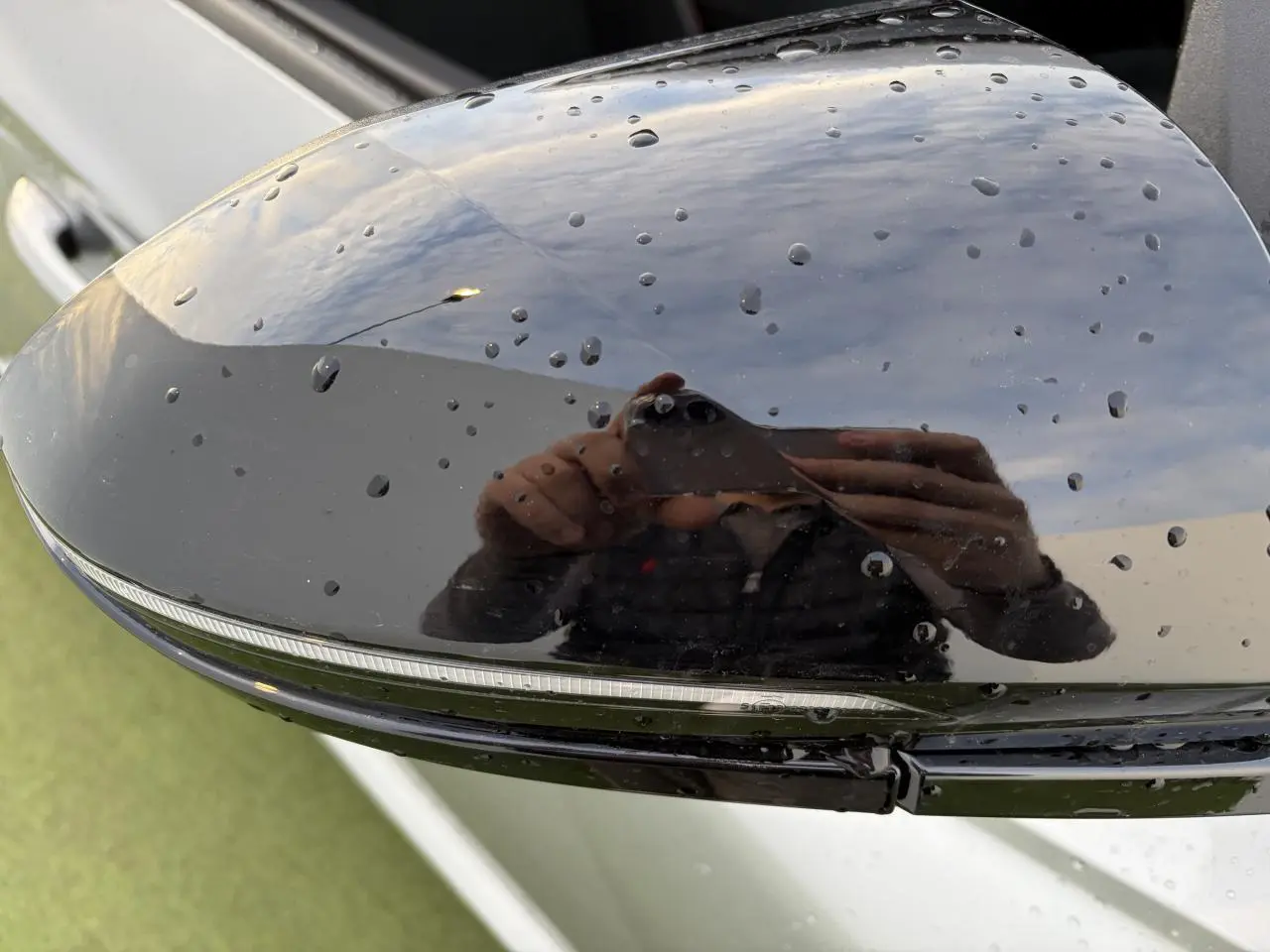 Gros plan sur le rétroviseur extérieur noir brillant du Hyundai Tucson 2025 en Shimmering Silver, avec gouttes d'eau visibles.