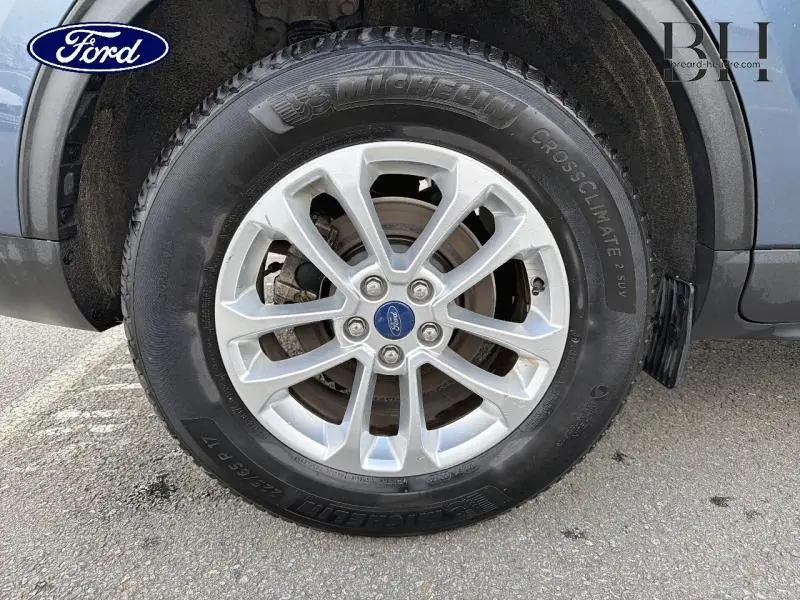 Gros plan sur la roue avant droite du Ford Kuga bleu azur métallisé avec jante alu et pneu Michelin CrossClimate.