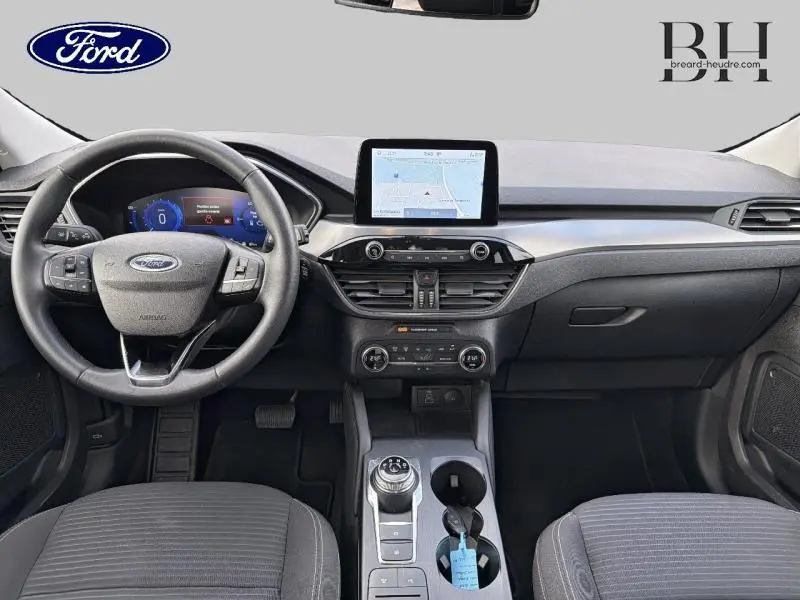 Vue intérieure avant du Ford Kuga 2022, tableau de bord noir avec écran tactile central et volant multifonction cuir.