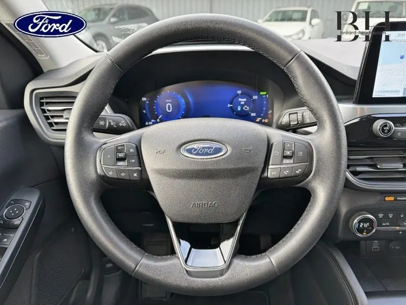 Vue rapprochée du volant cuir multifonction noir du Ford Kuga 2022 avec tableau de bord numérique et écran tactile latéral.