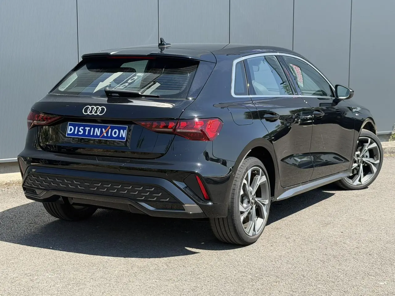Audi A3 Sportback noir Mythe vue 3/4 arrière droit, avec jantes alliage 5 branches en Y et feux arrière LED distinctifs.