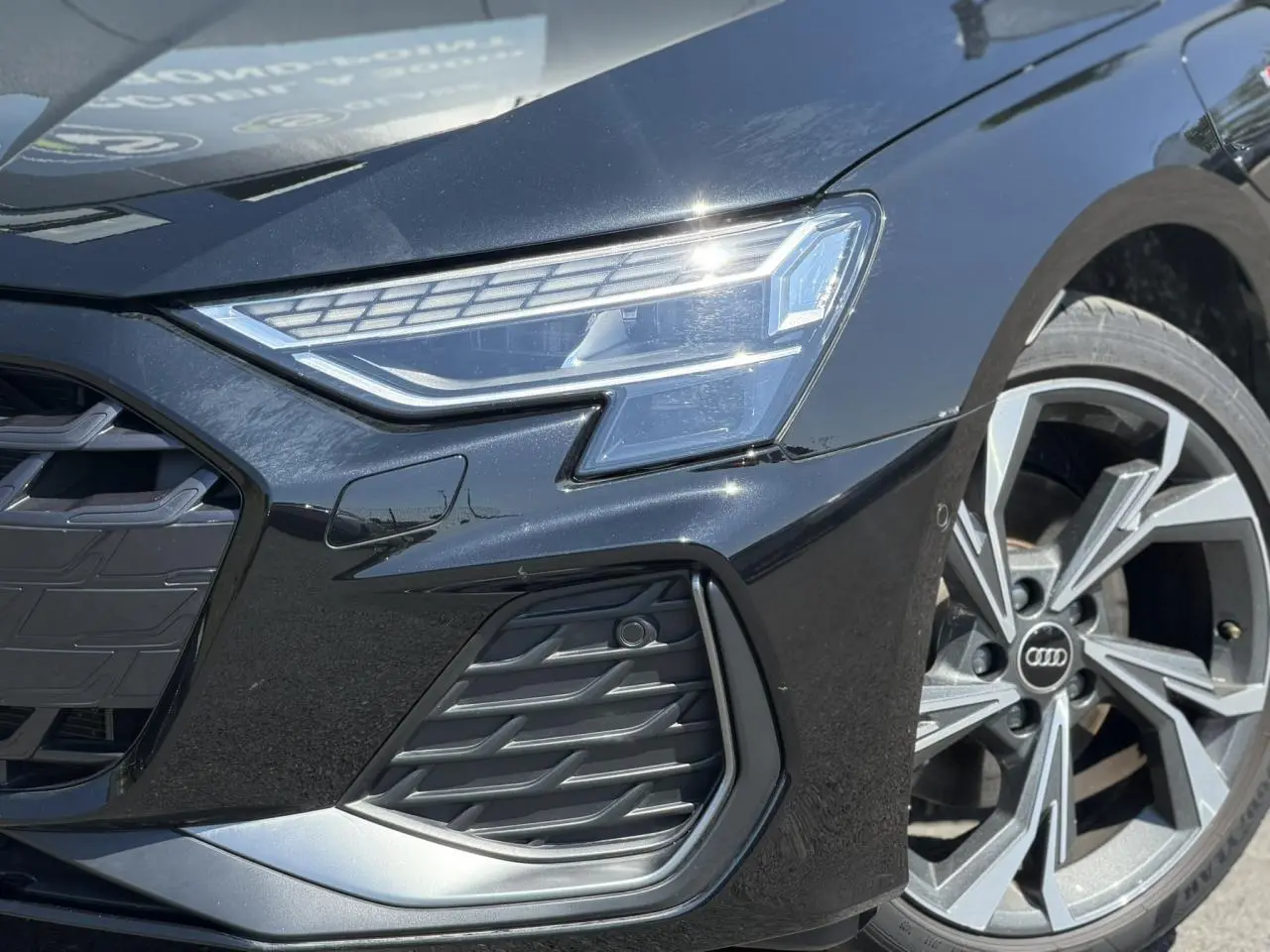 Gros plan sur l'avant droit noir Mythe de l'Audi A3 Sportback 2025 avec phares Matrix LED et jante alliage 5 branches en Y.