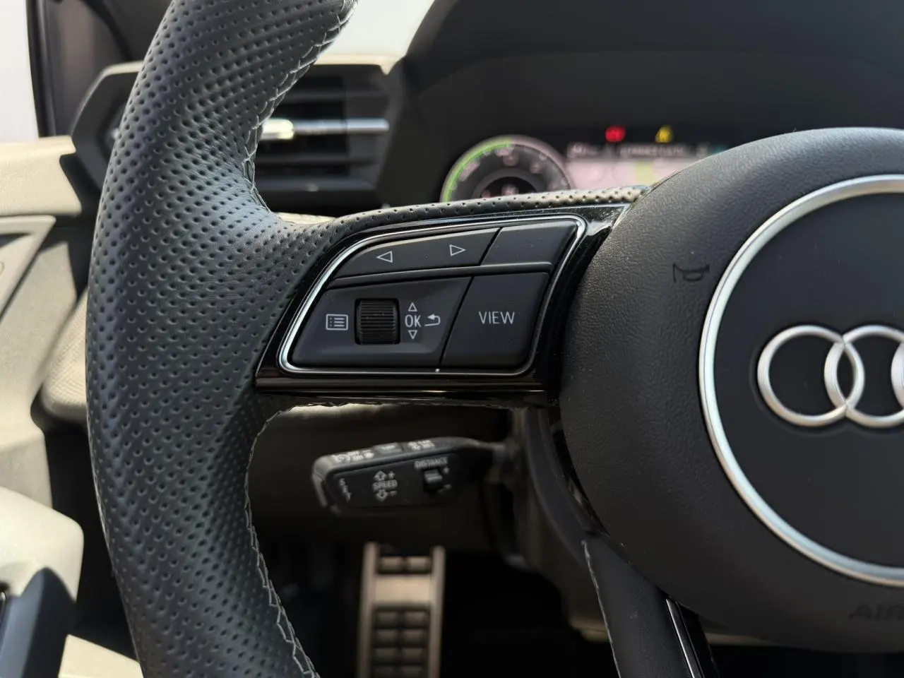 Gros plan sur le volant perforé noir de l'Audi A3 Sportback 2025 avec commandes multifonctions côté gauche.