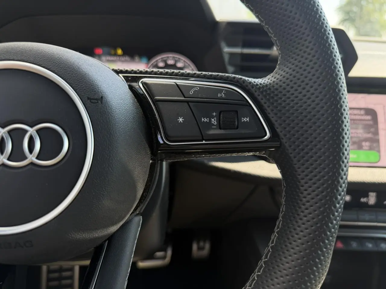Gros plan sur le côté droit du volant perforé noir de l'Audi A3 Sportback 2025 avec commandes multifonctions.