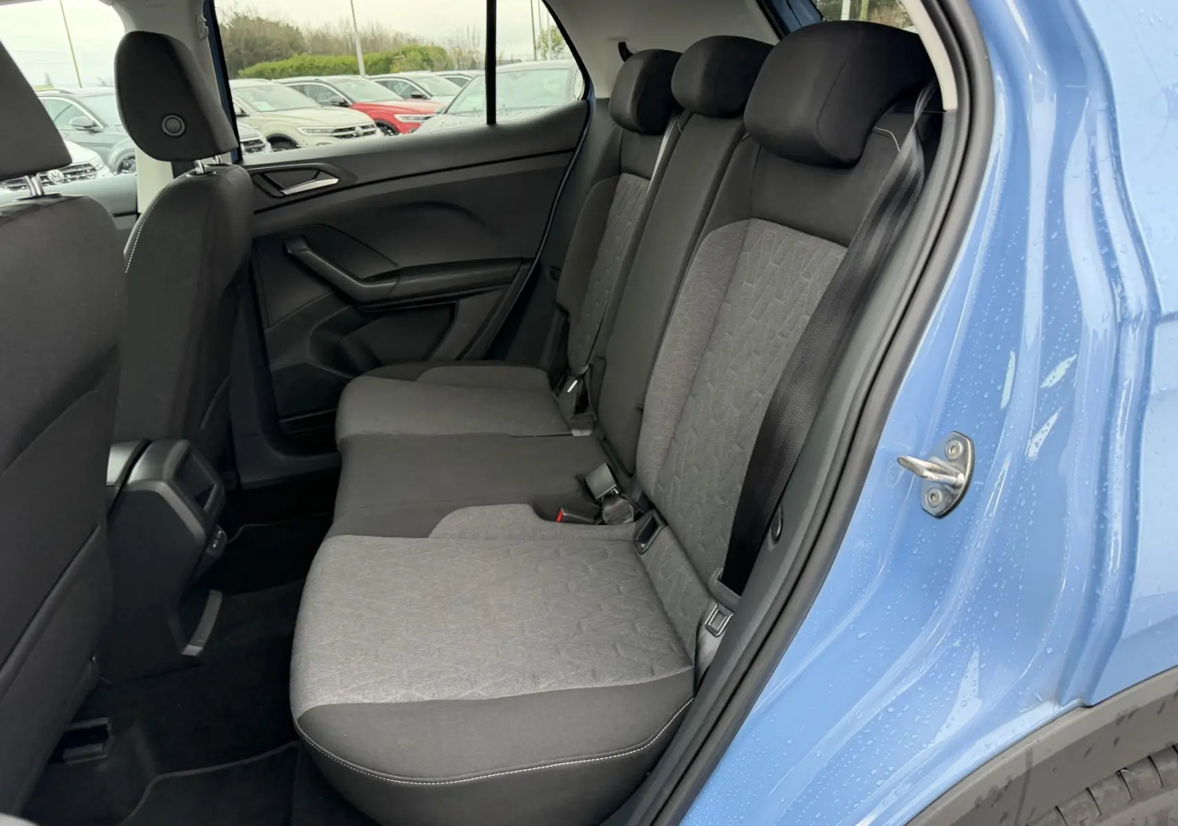 Vue intérieure côté droit des sièges arrière gris bi-ton du Volkswagen T-Cross bleu 2025 avec porte ouverte.